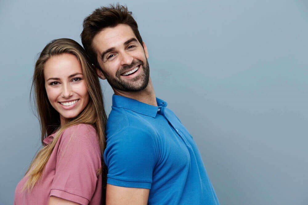 Young couple back to back smiling at the camera