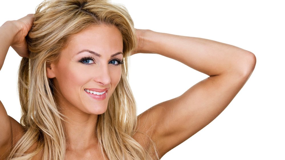 Blonde woman smiling and touching her hair