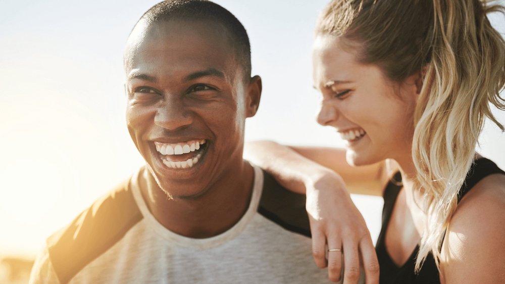 Man smiling with woman laughing leaning on on him