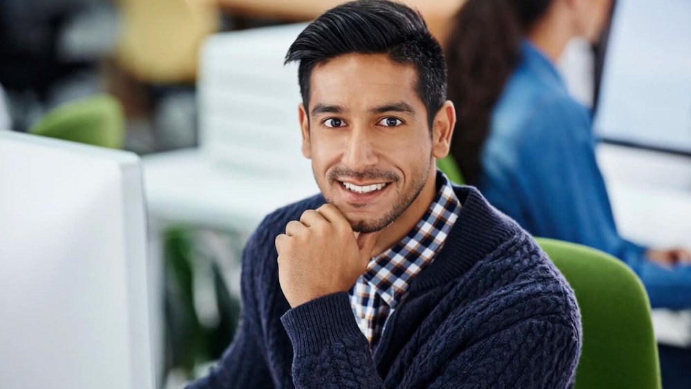 male rhinoplasty patient model sitting down wearing a blue sweater