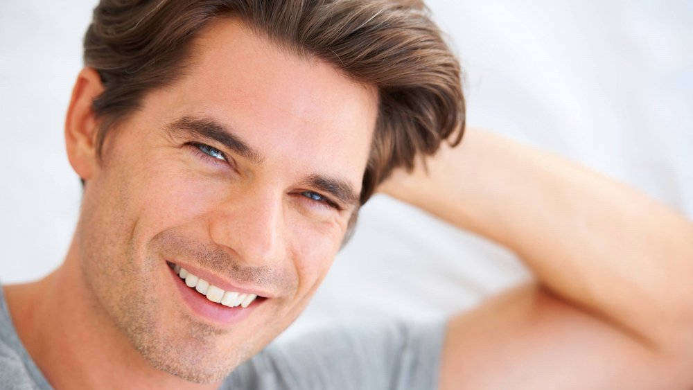 Man smiling with hand on head