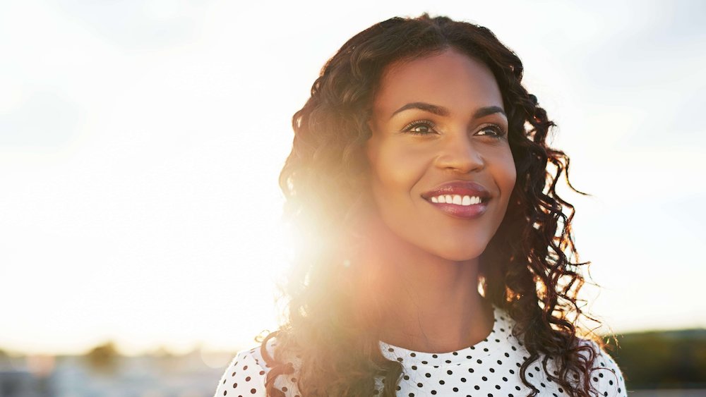 Woman smiling with sun behind her