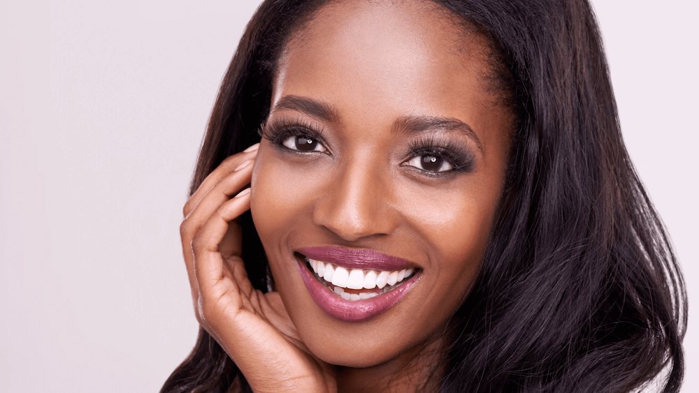 Woman smiling and putting her hand on her face.