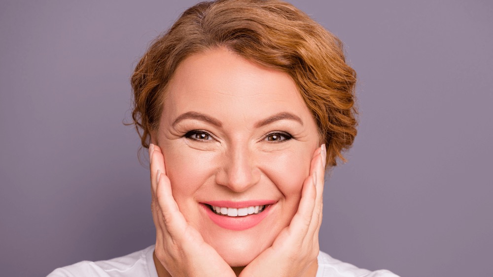 woman with hands on face with short redhair