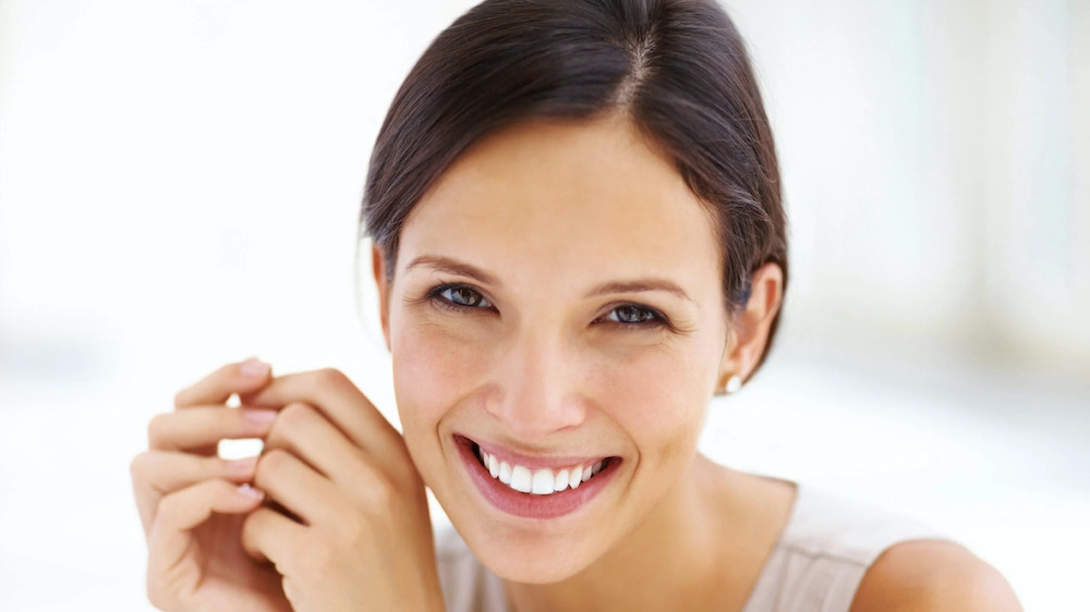 facelift patient model in a white tank top smiling widely